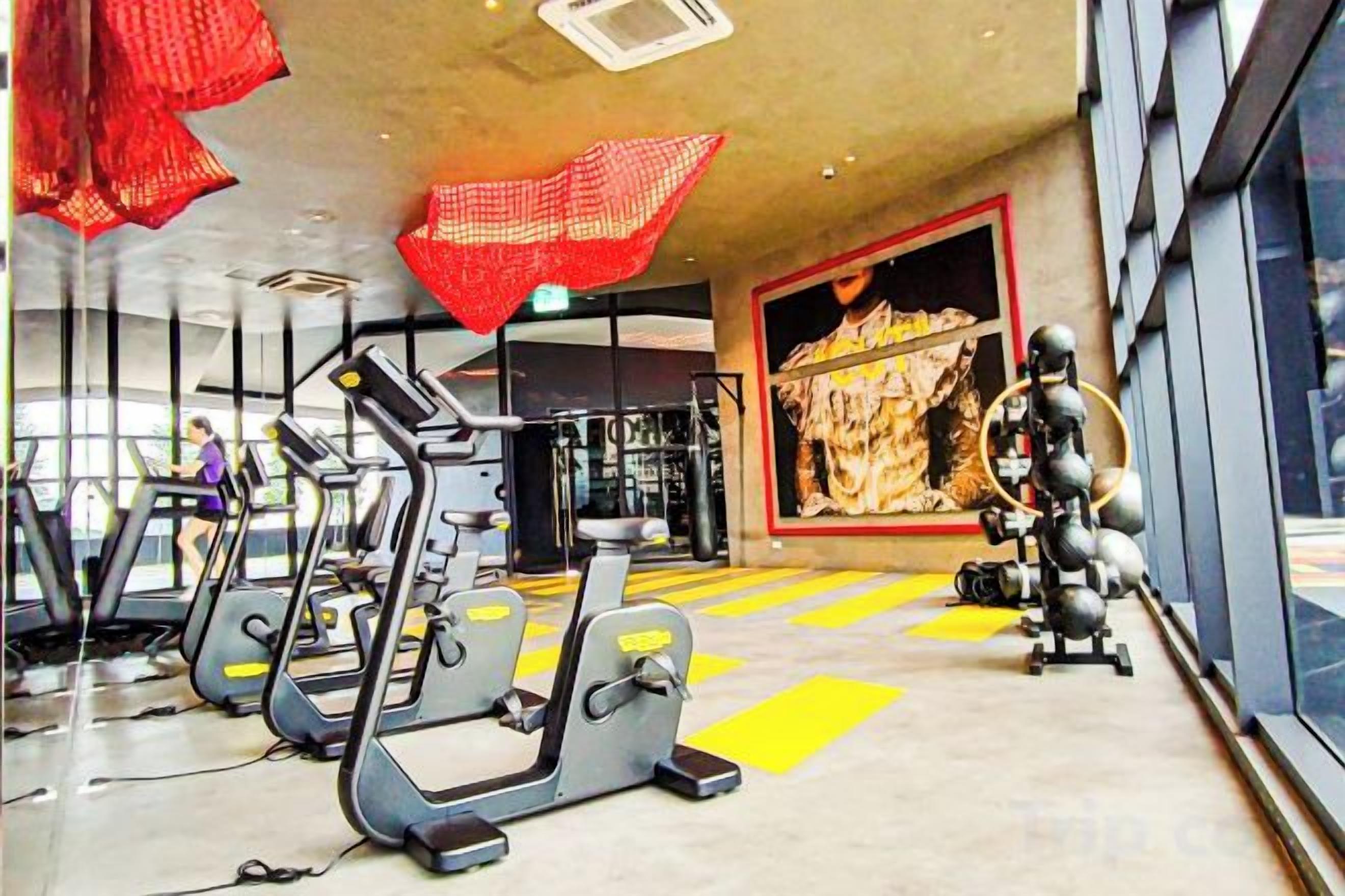 Un gimnasio con cintas de correr, máquinas de pesas y un gran mural en la pared.