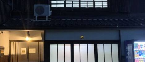 A building with a traditional Japanese architectural style, featuring a sliding door and a large window with a grid pattern.