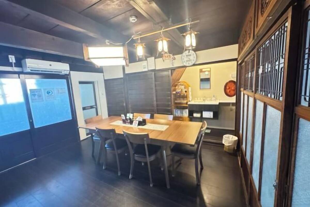 A dining area with a wooden table, chairs, and hanging lights.