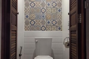 A bathroom with a toilet, a tiled wall, and wooden doors. - Dhub Hostel Donmueng (Bangkok)