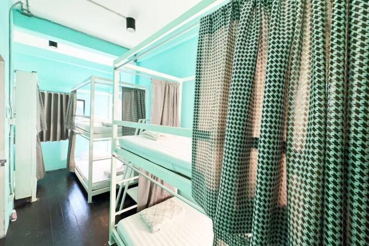 A bunk bed room with a window, a desk, and a patterned curtain.