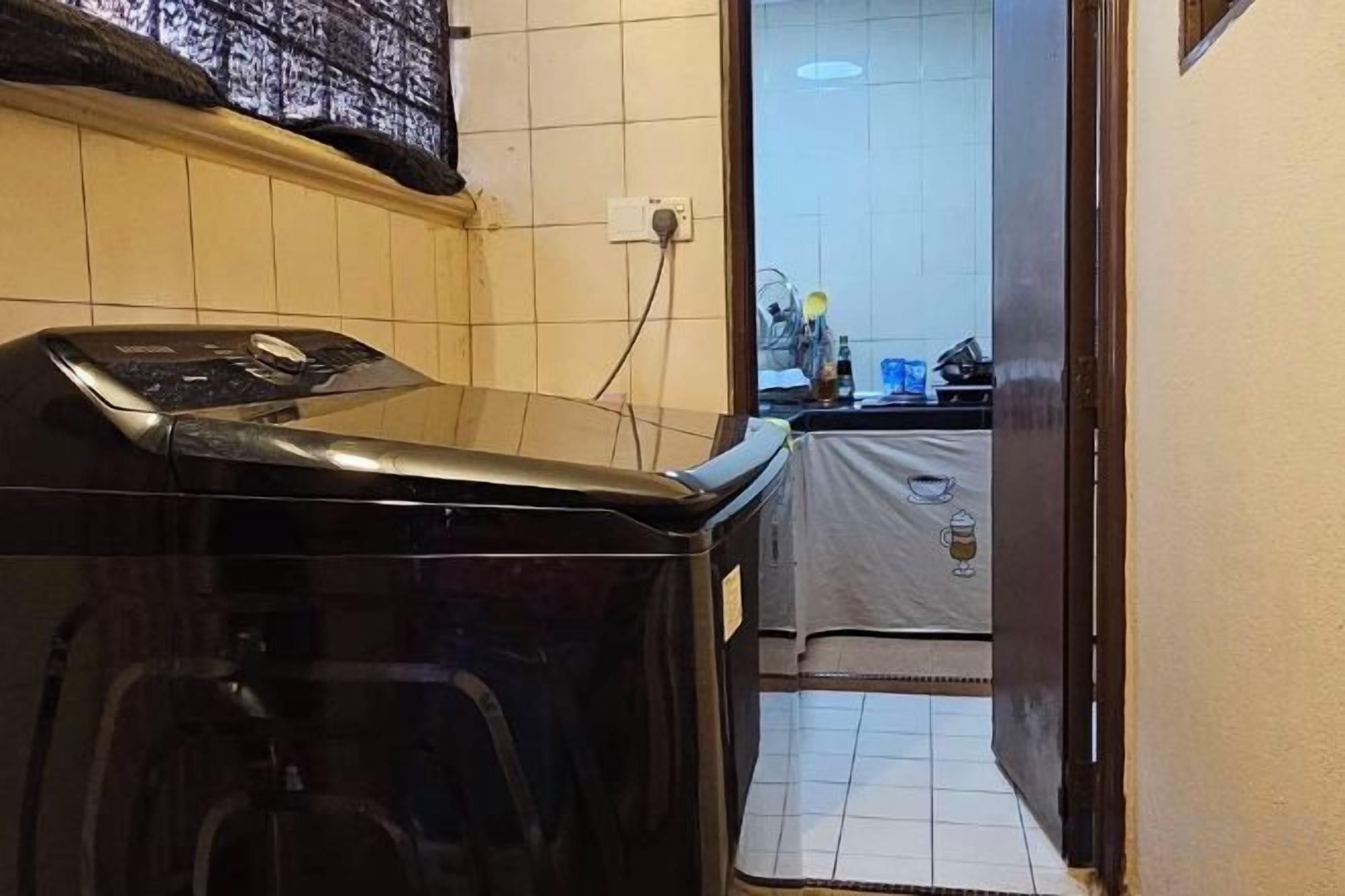 Une cuisine compacte équipée d’un lave-linge, d’un crédence carrelée et d’un petit coin repas.