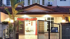 Une entrée fermée par un portail mène à une propriété dont le toit est recouvert de tuiles et sur laquelle est affiché un panneau indiquant un numéro de téléphone à contacter.