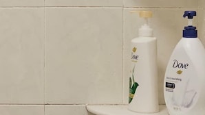 Två produkter från Dove för personlig hygien står på en vit hylla framför en vägg täckt med kakel.