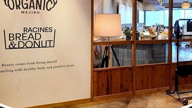 L’intérieur d’un restaurant, avec un séparateur en bois, une lampe et un comptoir où sont exposés des plats.