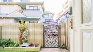 Une courClose, dotée d’un sol carrelé, d’une porte décorative et d’un petit jardin agrémenté de plantes et de fleurs.