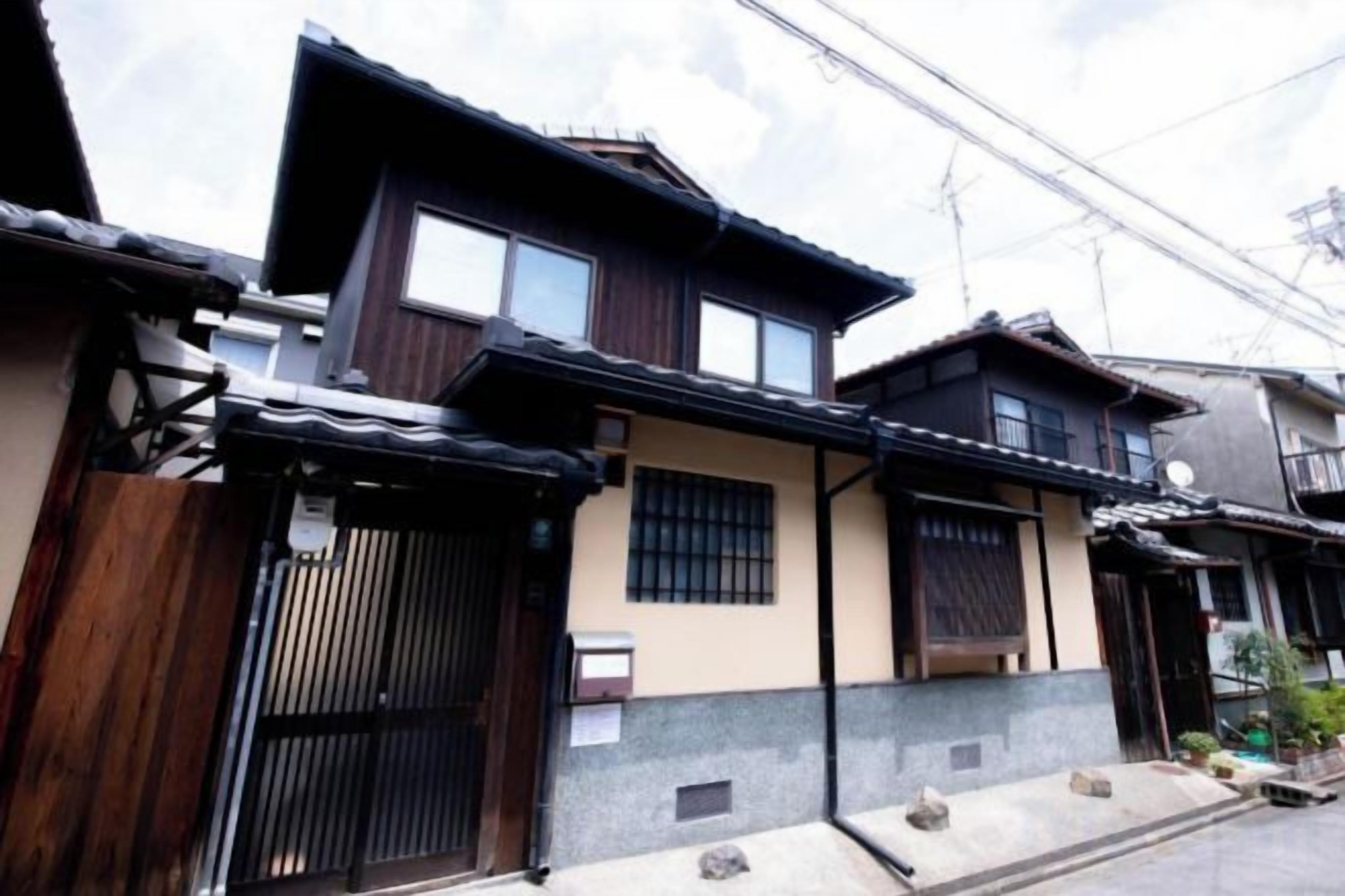 A traditional Japanese house with a wooden exterior, a tiled roof, and a gated entrance.