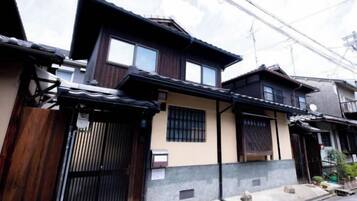 A traditional Japanese house with a wooden exterior, a tiled roof, and a gated entrance.