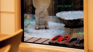 A pair of red and black slippers on a wooden bench outside a door. - Kyoya Nobuhiro Reisen (Kyoto)