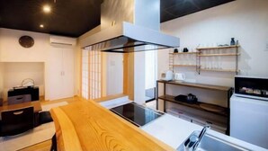 A modern kitchen with a wooden dining table, built-in appliances, and a minimalist design. - Kyoya Nobuhiro Reisen (Kyoto)