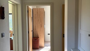 Ein Flur mit einer Holztür, einem kleinen Korbwäscher und einem weißen Schrank.
