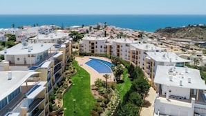 A residential area with a swimming pool surrounded by greenery and buildings. - BnB Homes Ocean View Apartment with relax Terrace, 2 Swimming pools & Tennis court (Albufeira)