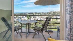 A balcony with a table, chairs, and an umbrella, overlooking a scenic view. - BnB Homes Ocean View Apartment with relax Terrace, 2 Swimming pools & Tennis court (Albufeira)