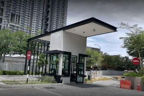 A modern building with a glass entrance, surrounded by greenery and tall residential buildings. - D'sands Residences Midvalley (Kuala Lumpur)