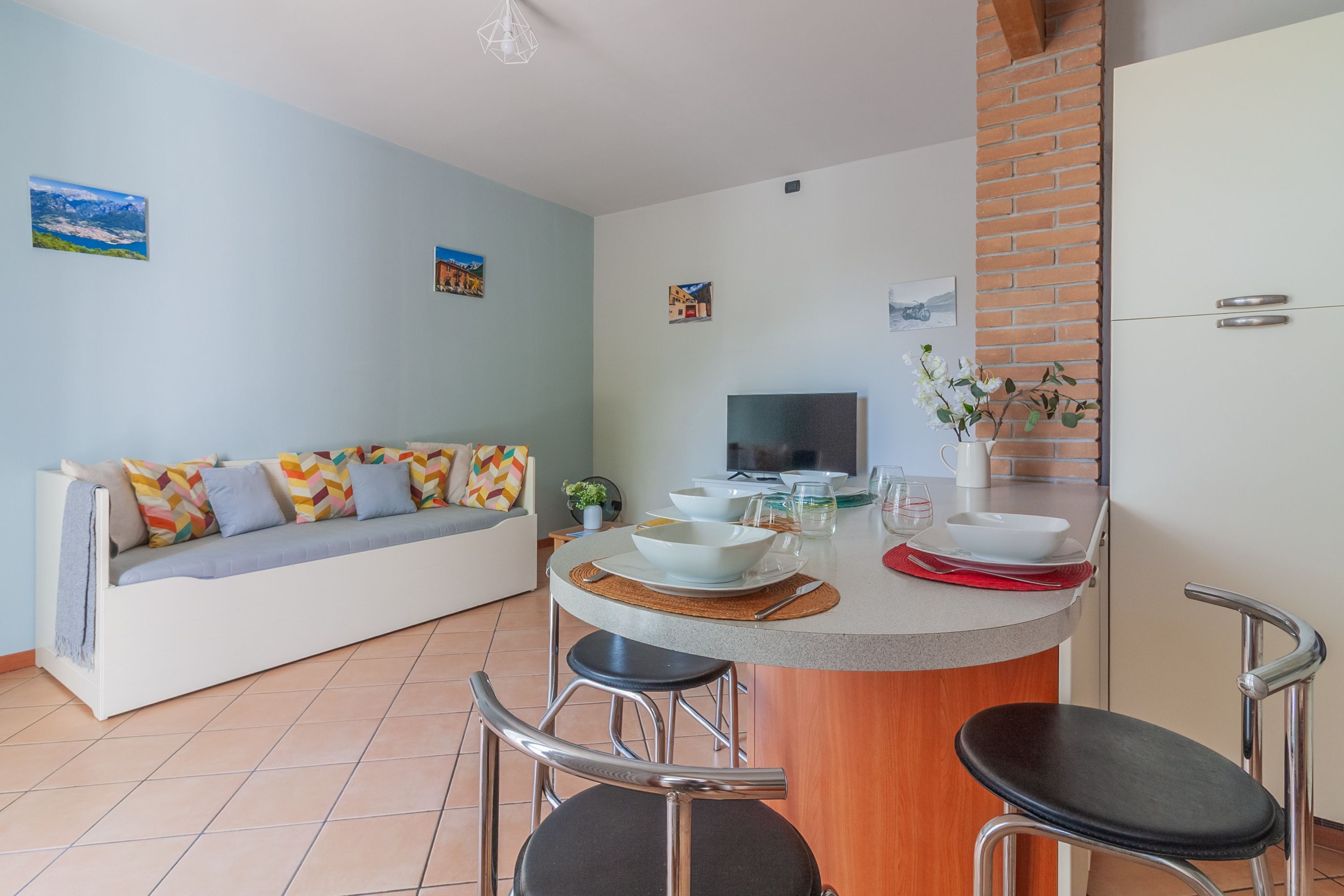 Un espace de vie compact comprenant un canapé, un petit coin cuisine avec une table à manger et un téléviseur.