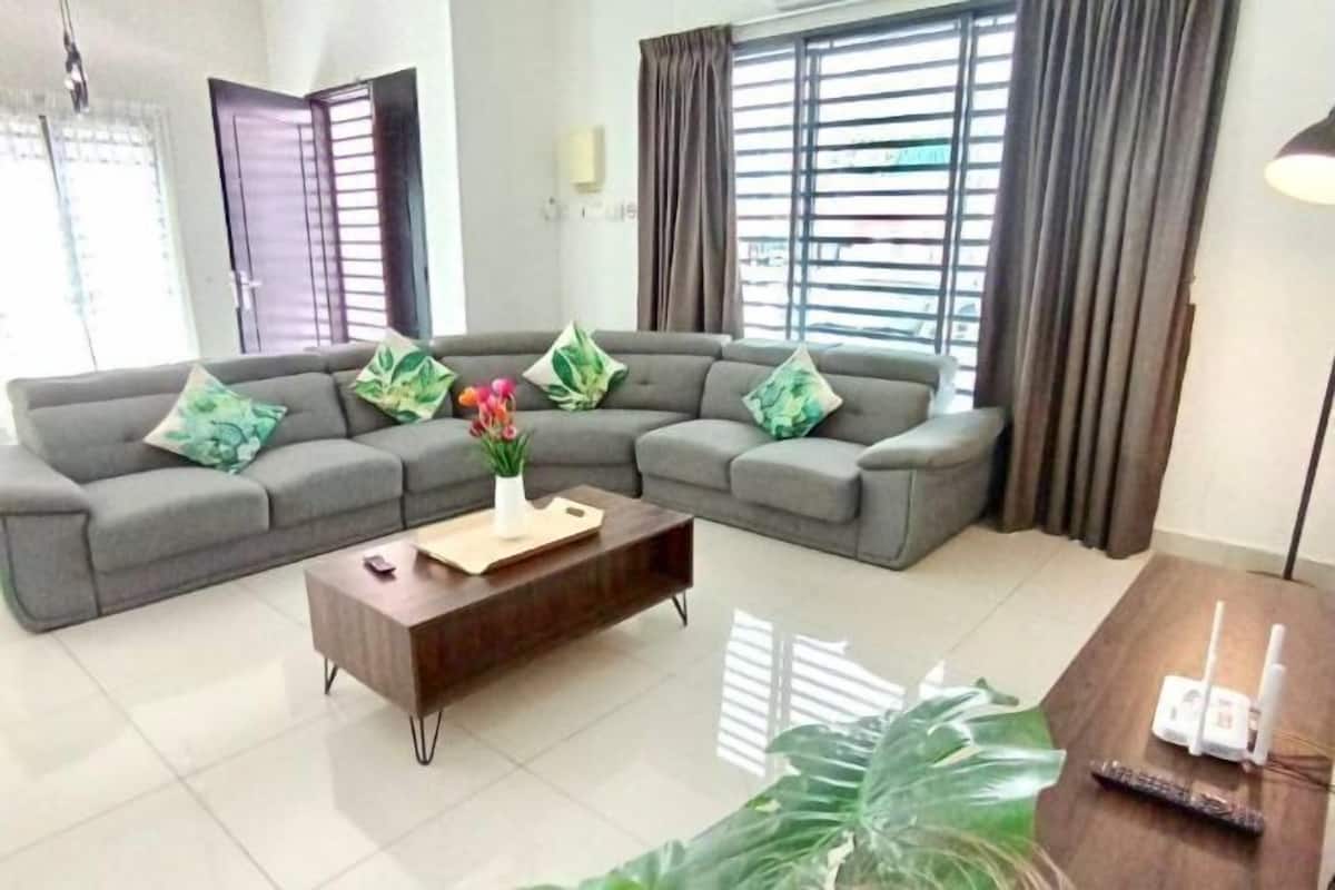 A modern living room with a grey sectional sofa, a wooden coffee table, and a large green plant.