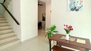 A staircase leading to a dining area with a table and chairs, a ceiling fan, and a framed artwork on the wall. - Tropical Livings Meru Ipoh Homestay (Ipoh)