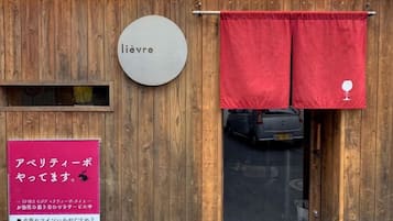 Fachada de madera con un letrero que dice 'lievre' y una cortina roja con el símbolo de una copa de vino.