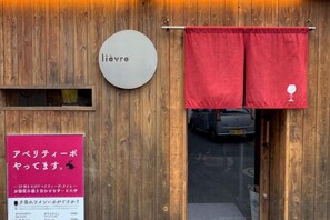 A wooden exterior with a sign reading 'lievre' and a red curtain with a wine glass symbol. - SunStay Higashinakano (Tokyo)