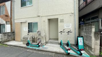 Un edificio con zona de estacionamiento, cartel y estación de carga para scooters.