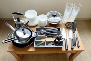Une table avec du matériel de cuisine, notamment des casseroles, des poêles, des assiettes et des ustensiles.