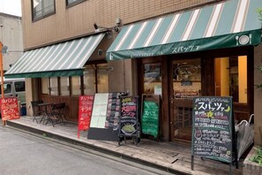A restaurant with a green awning and outdoor seating. There are signs with menu items and prices. - SunStay Higashinakano (Tokyo)