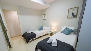 A hotel room with two single beds, a nightstand with a lamp, and a door leading to another room. - Duplex in Gelves with private pool and large terrace, near Seville (Gelves)