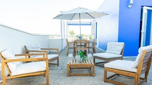 A rooftop patio with wooden furniture, a table with wine glasses, and a large umbrella. - Duplex in Gelves with private pool and large terrace, near Seville (Gelves)