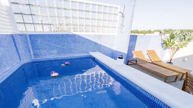 A swimming pool with blue mosaic tiles, two wooden lounge chairs, and a small plant. - Duplex in Gelves with private pool and large terrace, near Seville (Gelves)