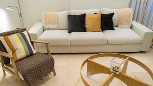 A living room with a sofa, a chair, and a round wooden coffee table. - Duplex in Gelves with private pool and large terrace, near Seville (Gelves)