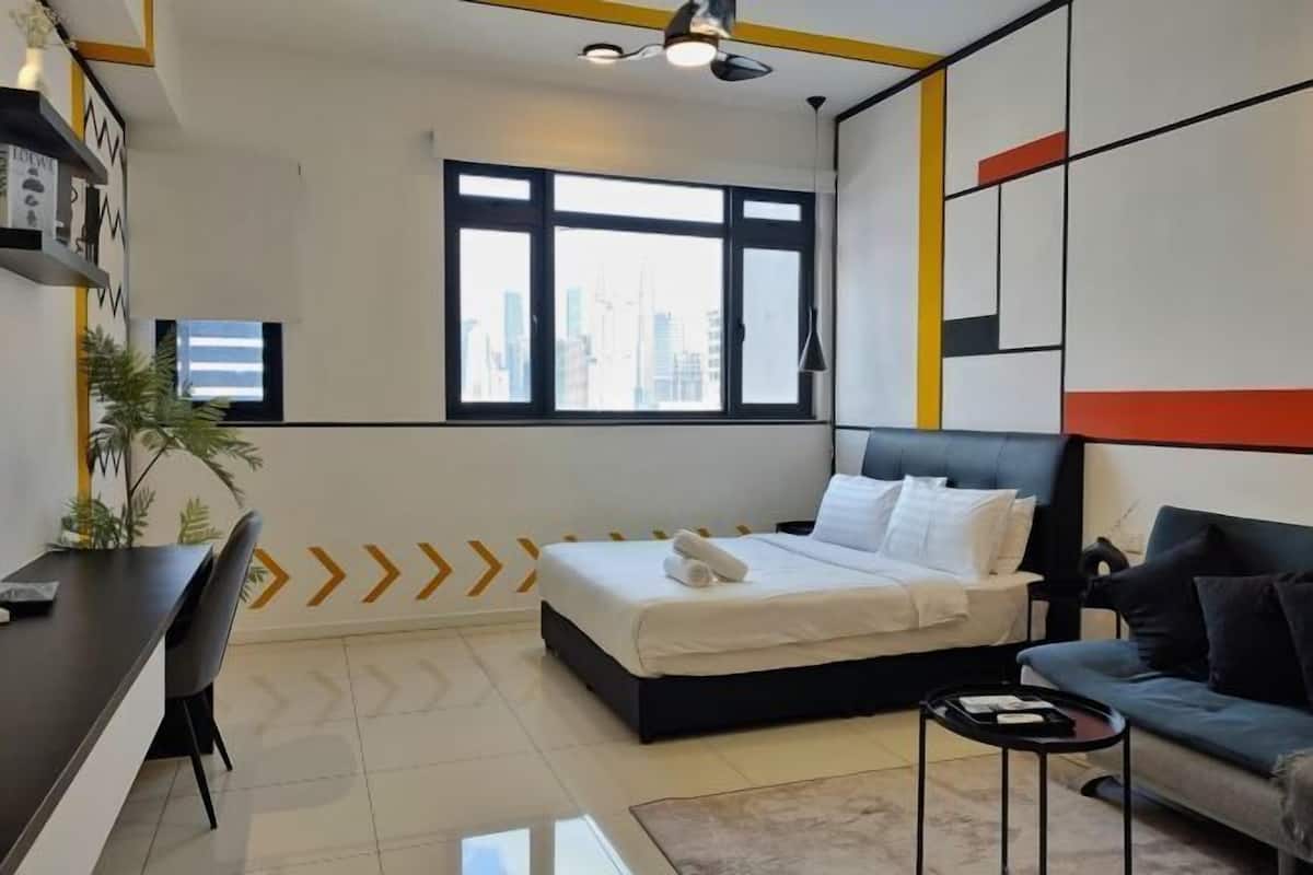 Une chambre d’hôtel moderne équipée d’un lit, d’un bureau, d’un canapé, d’une grande fenêtre et offrant une vue sur la ville.