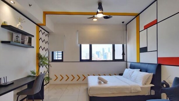 Habitación de hotel moderna con cama, escritorio y silla. Cuenta con una ventana con vistas a la ciudad y un diseño limpio y minimalista.