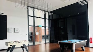 Una habitación con mesa de billar, mesa de fútbol y amplias ventanas.