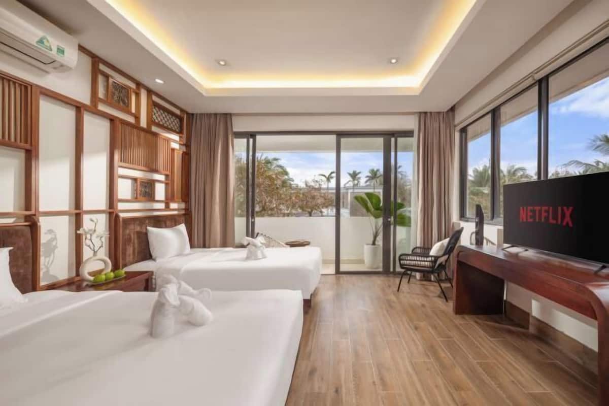 Ein Hotelzimmer mit zwei Betten, einem Fernseher und einem Balkon mit Blick.