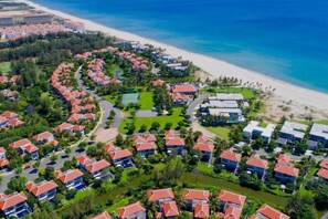 Luchtbeeld van een resort met meerdere gebouwen, een strand en een heldere blauwe oceaan.