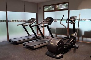 Une salle de sport équipée de tapis de course, d’un vélo elliptique et d’un vélo d’appartement.