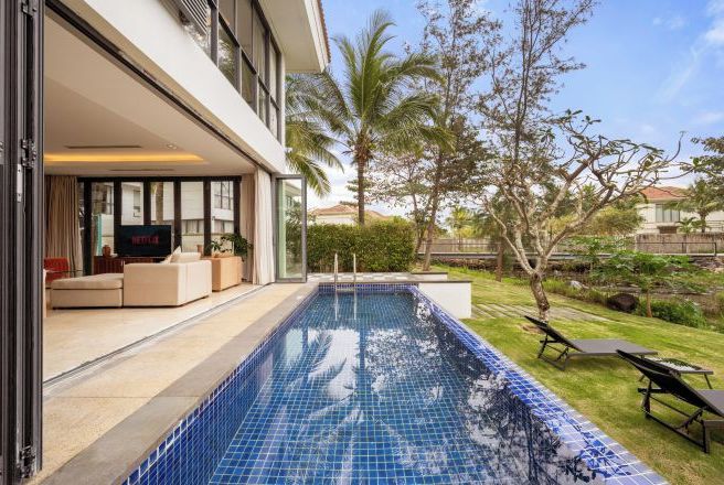 A modern house with a swimming pool, outdoor seating, and a well-maintained garden.