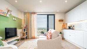A modern living room with a sofa, TV, and a view to the outside. - The Eades Laura Perryman 1 Bed (London)