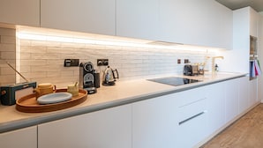 A modern kitchen with white cabinets, a wooden countertop, and a built-in oven. - The Eades Laura Perryman 1 Bed (London)