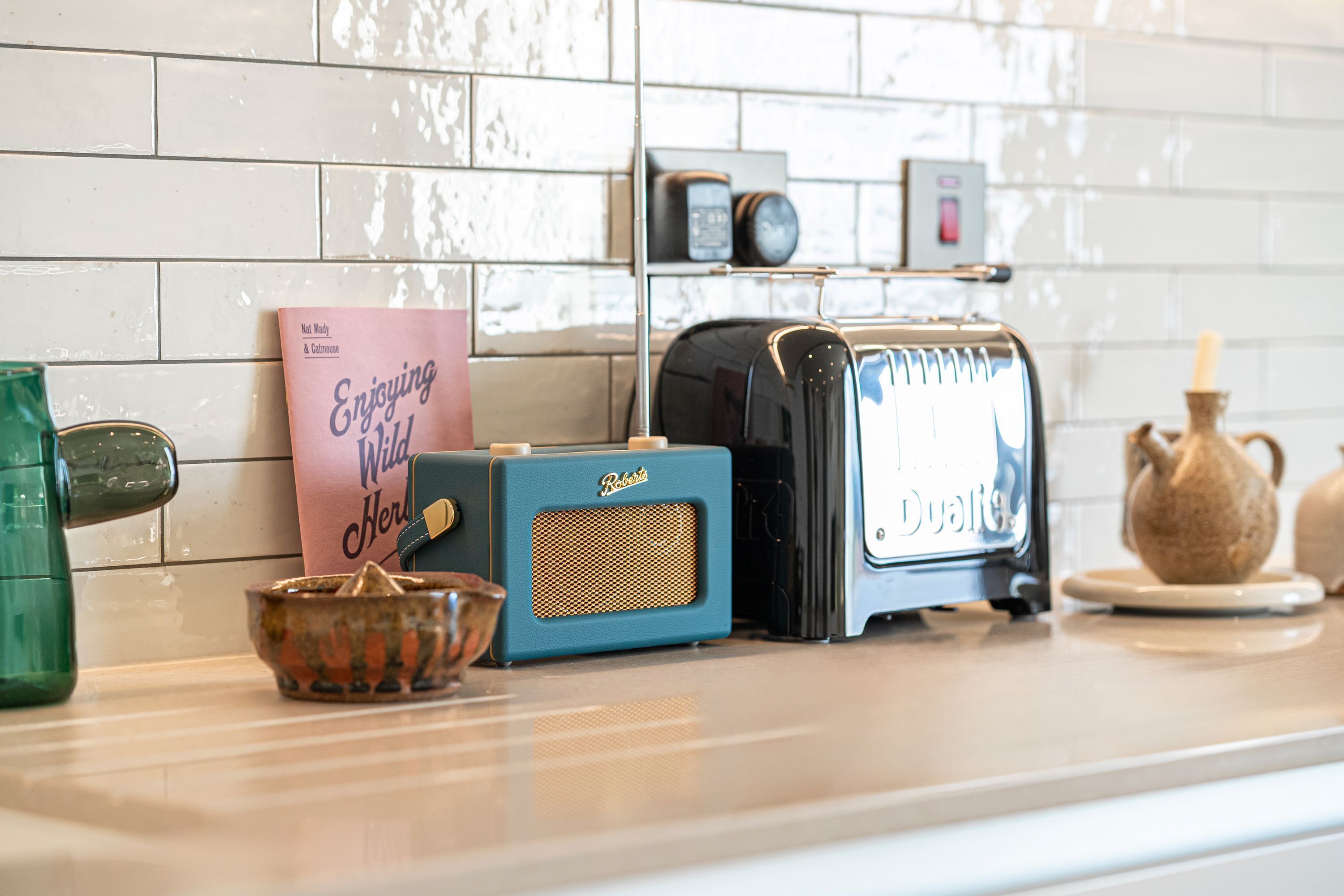 A kitchen counter with vintage radios, a book, and a teapot.