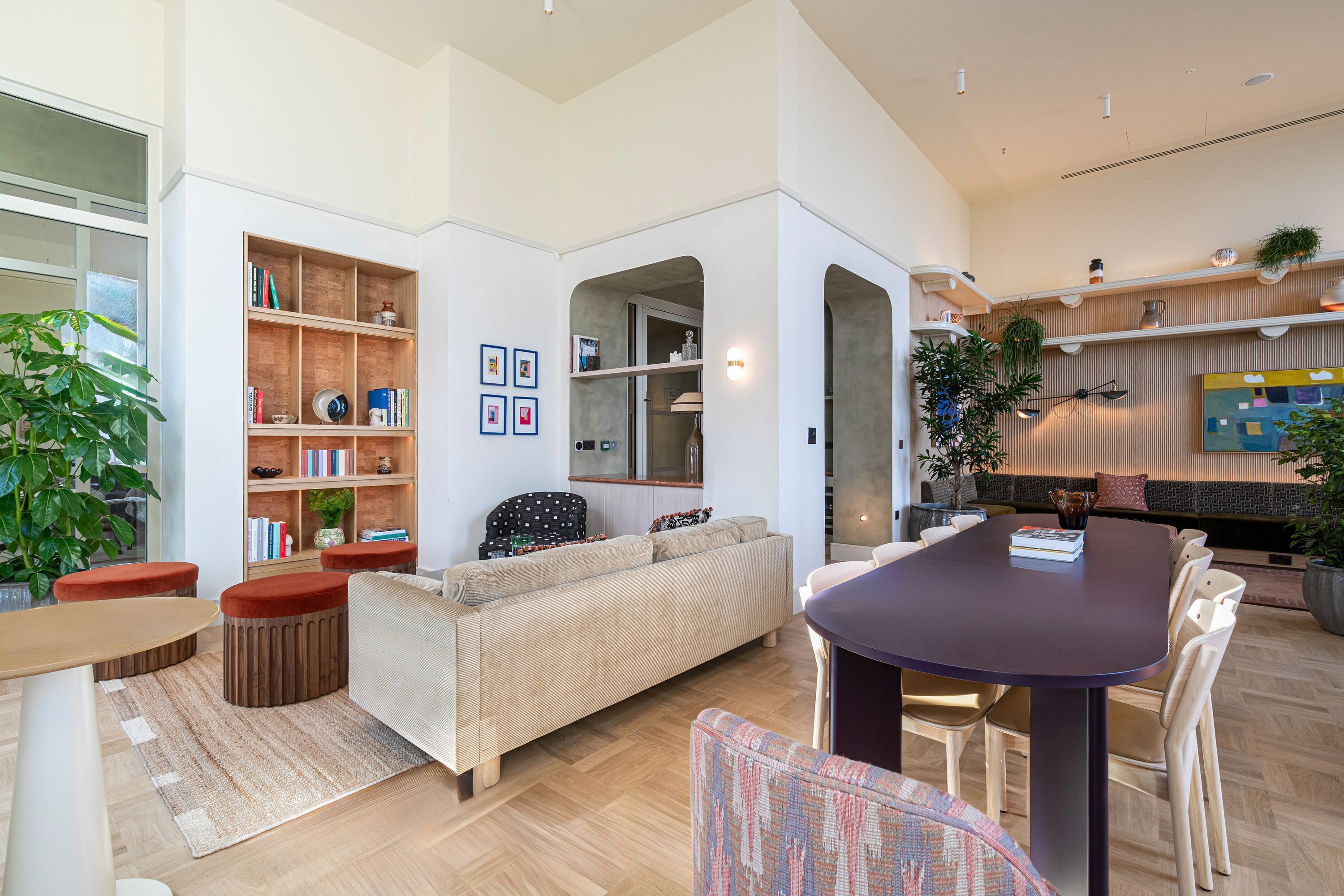A modern living room with a sofa, a dining table, and a bookshelf.