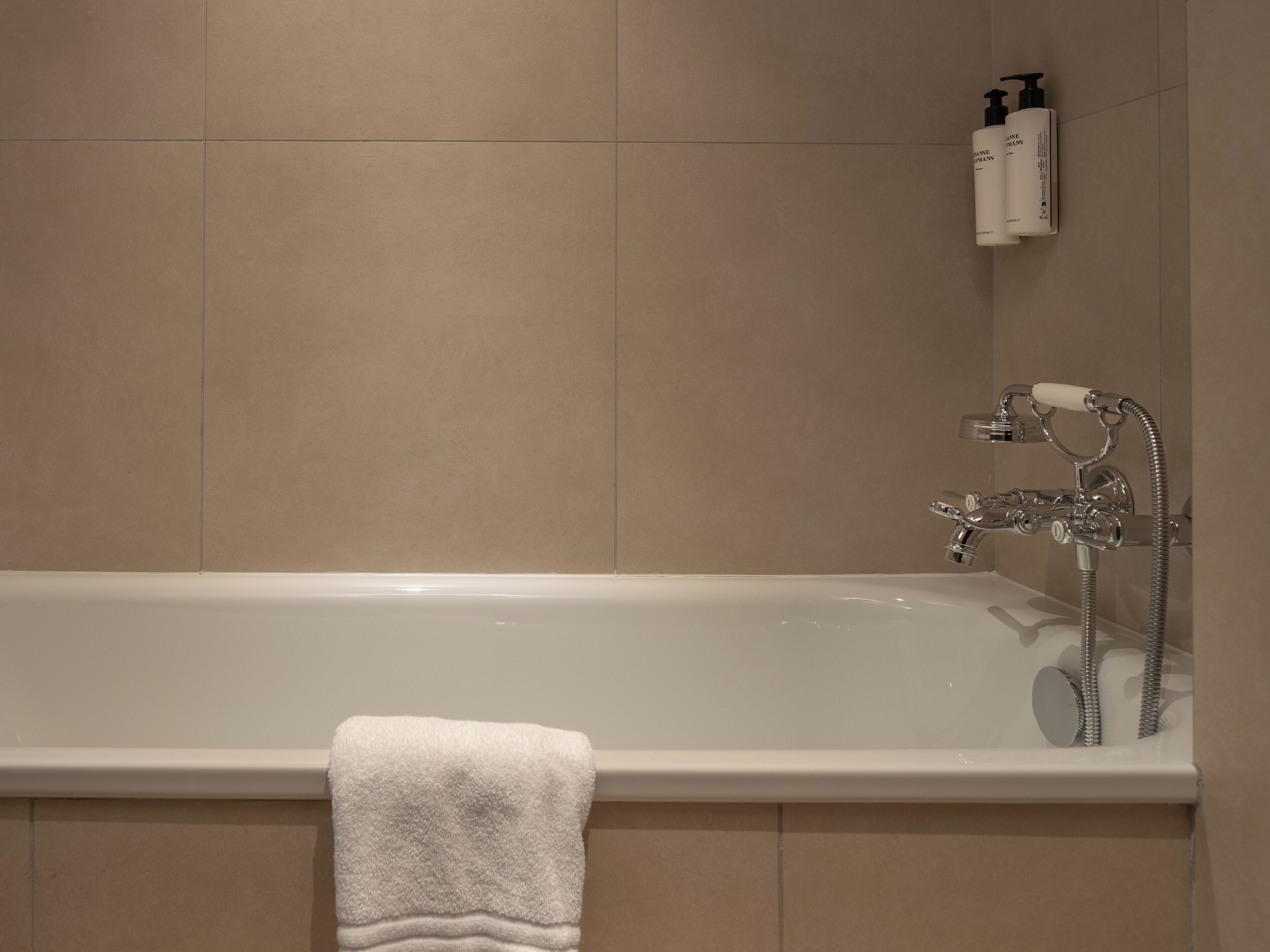 Une salle de bain avec une baignoire, une serviette et des articles de toilette accrochés au mur.