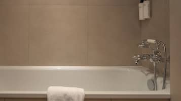 Une salle de bain avec une baignoire, une serviette et des articles de toilette accrochés au mur.
