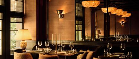 A dimly lit restaurant with wooden furniture, hanging paper lanterns, and a large mirror reflecting the interior.