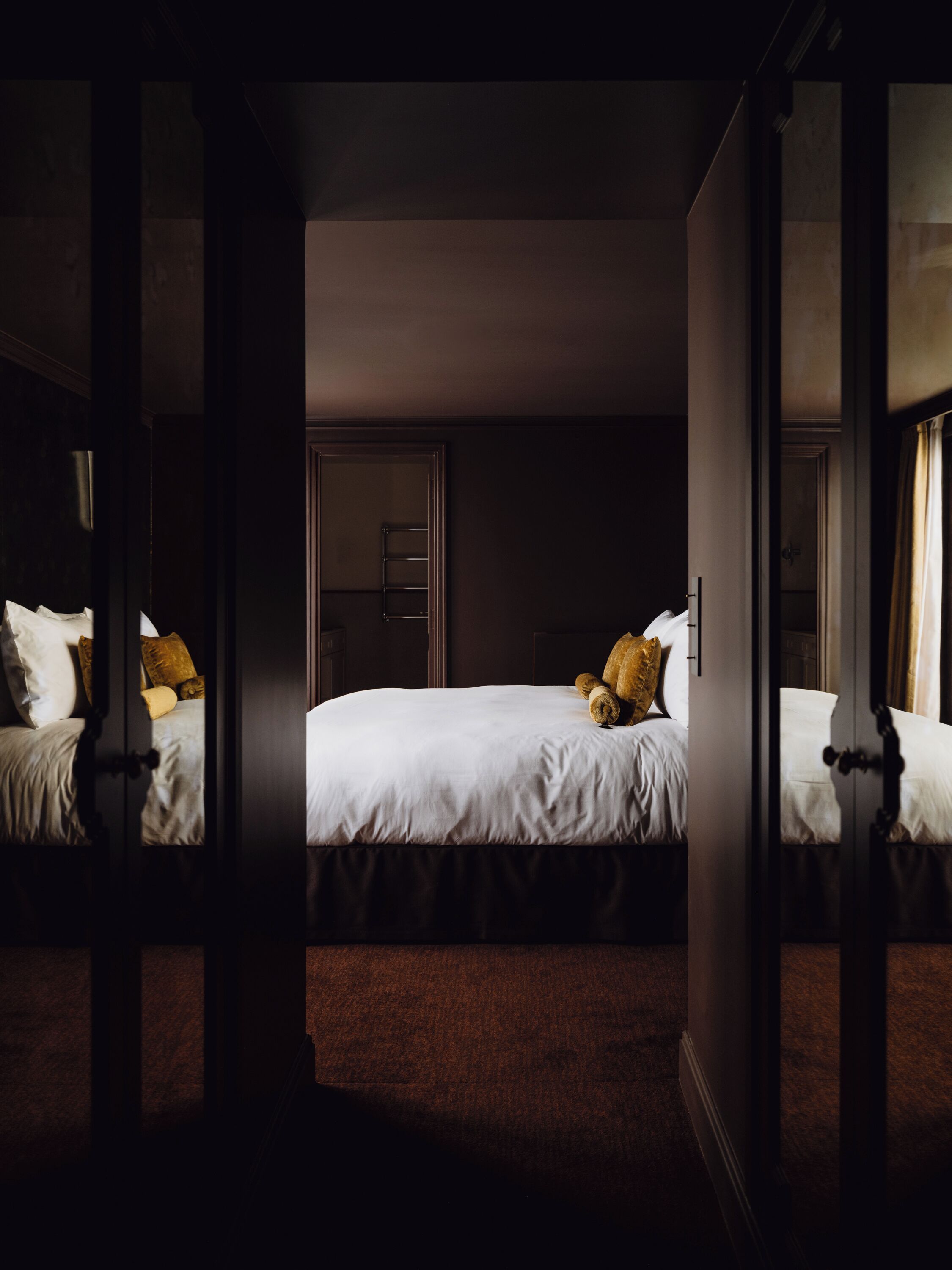Et hotelværelse med en seng, et garderobeskab og et spejl der afbilder værelset.