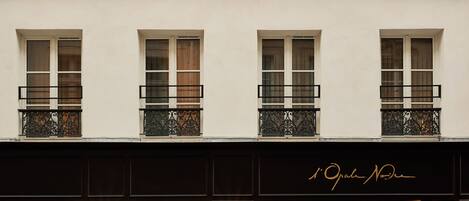 A building with multiple windows and balconies, featuring a black storefront with illuminated signage.