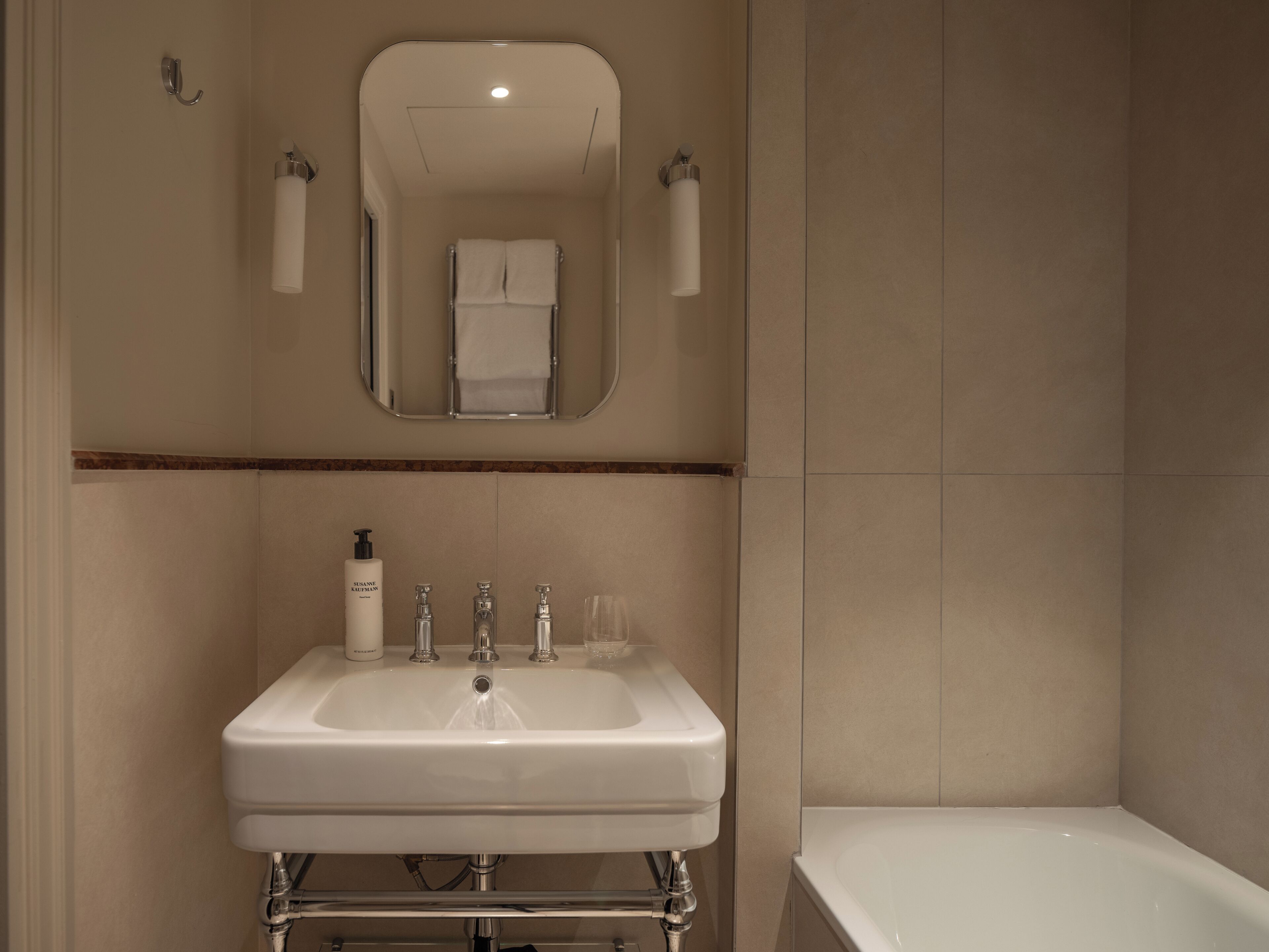 A bathroom with a white sink, a mirror, and a bathtub.