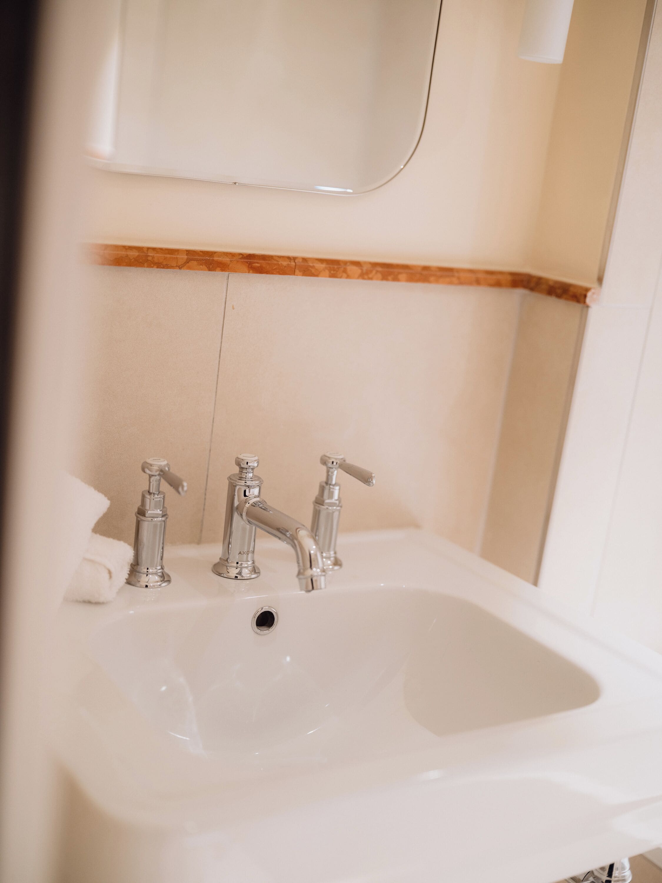 A bathroom with a white sink, two faucets, and a mirror above it.