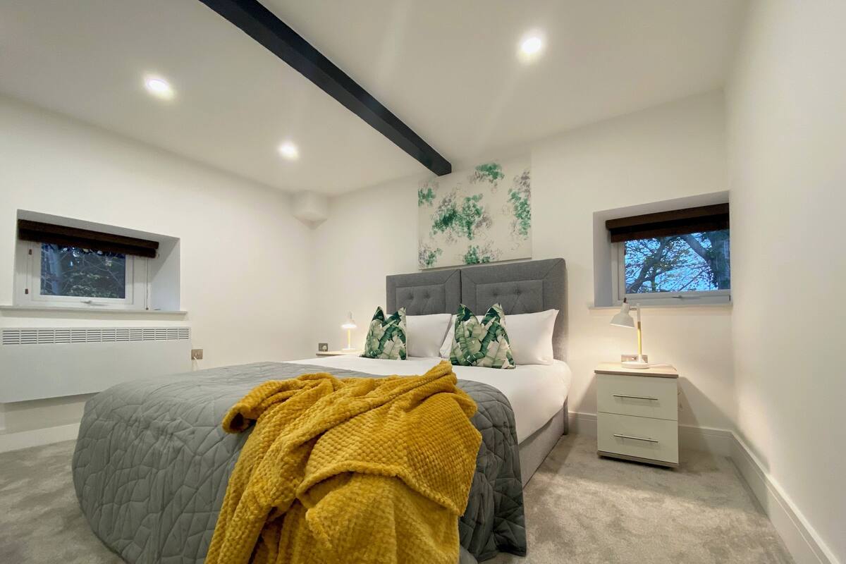 A bedroom with a bed, bedside tables, a window, and a radiator.