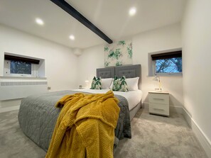 Un dormitorio con cama, mesitas de noche, una ventana y un radiador.
